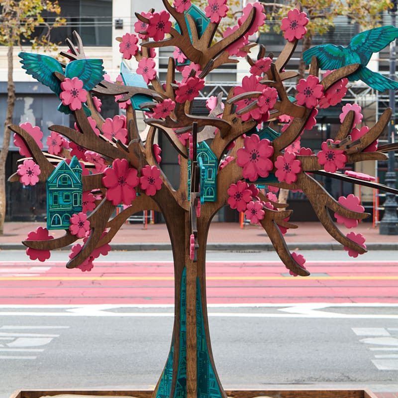Zen Treehouse by Serge Gay Jr. on Market Street: a carved wooden tree with pink blossoms, teal birds and small teal houses in its branches.